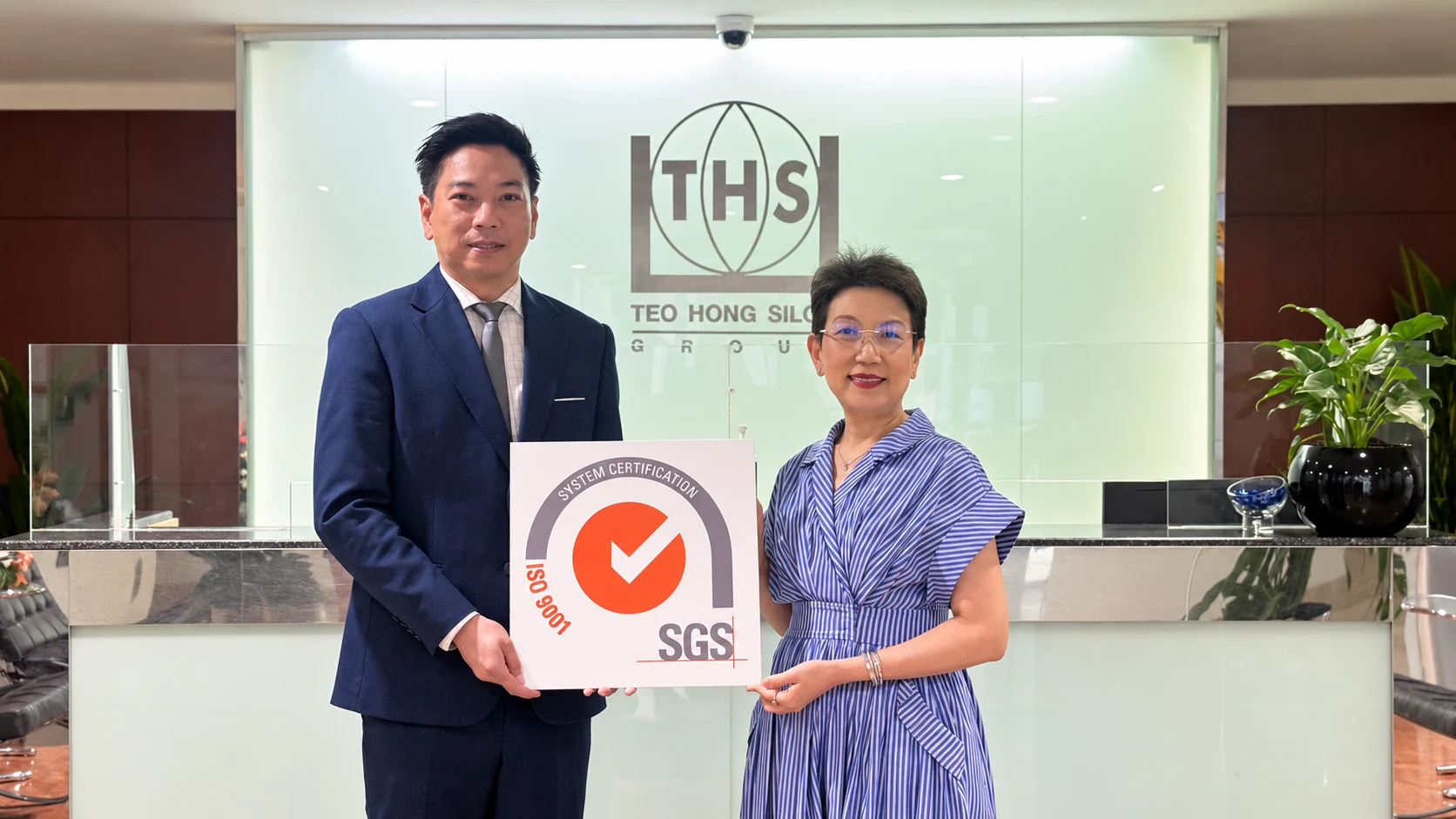Ms. Kanyakorn Sirirat-Asdon holding the ISO 9001 certification sign from SGS